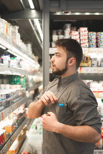 Homem feliz vestindo uma camisa fica na geladeira no leite — Fotografia de Stock