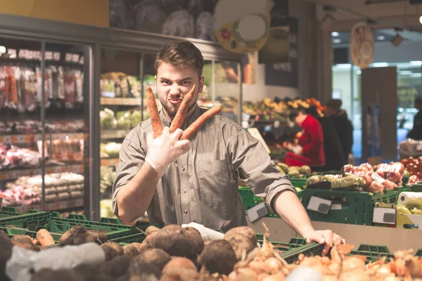 Человек держит две морковки в супермаркете — стоковое фото