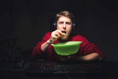 Konsantre genç adam odada gece oturur, bir bilgisayarda film izlerken ve yeşil bir yemek snack yeme. Adam cips yiyor ve karanlık bir Roo arka planda bilgisayar ekranına odaklanmış görünüyor