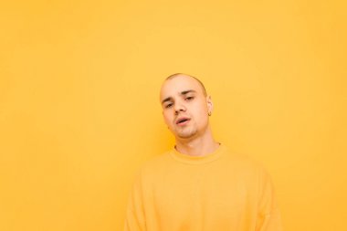 Sarı giysiler giyen kel bir kafa ile şık genç adam pozlar 