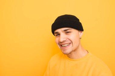Mutlu genç adam dişleri üzerinde bir Grillz ile gülümsüyor, bir şapka giyiyor