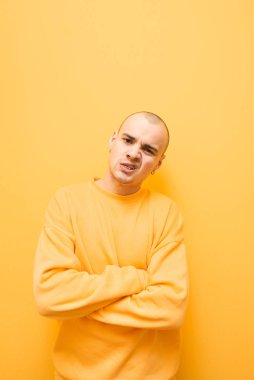 Parlak kıyafetlerle karizmatik bir adamın portresi, sarı bir arka planda agresif bir yüz yapar ve kameraya bakar. Dişleri üzerinde Grillz ile Evil şık adam kameraya pozlar. Izole