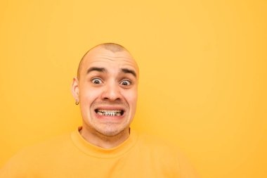Dişleri üzerinde Grillz deli adam yakın yukarı portre komik bir yüz yapar ve sarı bir arka planda kamera bakarak şok. Sarı giysiler bir tilki kafası ile çılgın genç adam