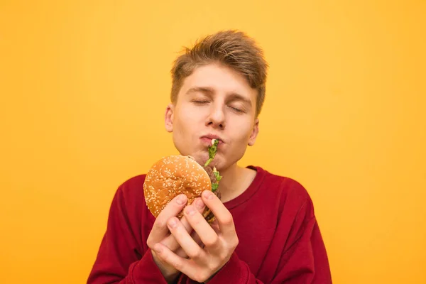 Hungriger Student in legerer Kleidung steht auf einem gelben Backgr — Stockfoto