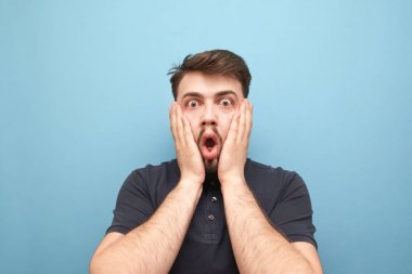 Korku karşısında bir el aldı sürpriz bir adamın yakın çekim portre, mavi bir arka planda kamera içine duygusal görünüyor. Mavi bir duvarın arka planında sakal olan şok bir adamın portresi