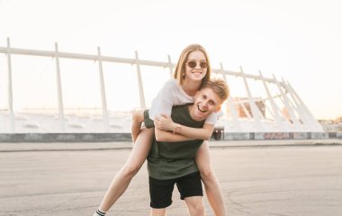 Bir çift şehir manzara etrafında yürüyen bir aşık, gülümseyen, çocuk arkada kız tutar, o ona sarılıyor ve gülümsüyor. Genç adam veren piggyback binmek için kız arkadaş, sahip olan eğlence