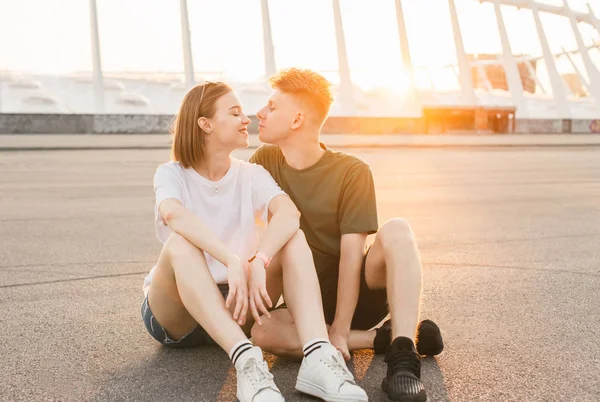 Bella bella coppia di relax sullo sfondo della città al tramonto, abbracci e baci seduti sull'asfalto la sera. Coppia elegante all'appuntamento. Stile di vita Concetto . — Foto Stock