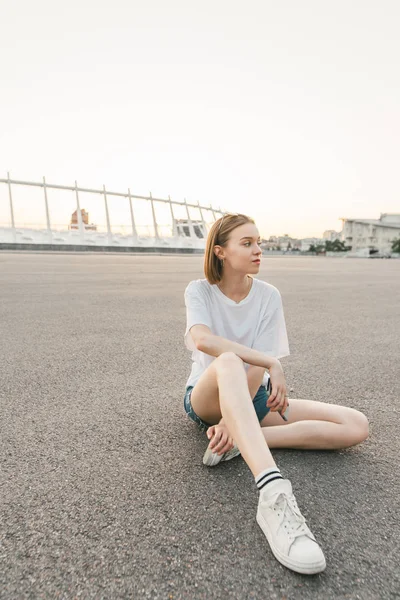 Retrato nocturno de una chica atractiva con una cara seria mirando hacia los lados. Una hermosa chica bien vestida con ropa casual posa a la cámara . —  Fotos de Stock