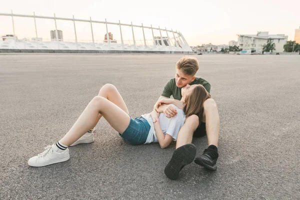 Retrato retrato de um belo casal de amantes abraçando na rua em um lugar deserto contra o pano de fundo da paisagem urbana. Retrato de rua de um jovem casal beijando em uma noite de verão . — Fotografia de Stock