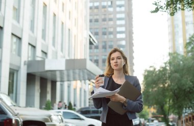 Meşgul kadın ofis çalışanı kahve, dizüstü bilgisayar, belgeler bir fincan tutan