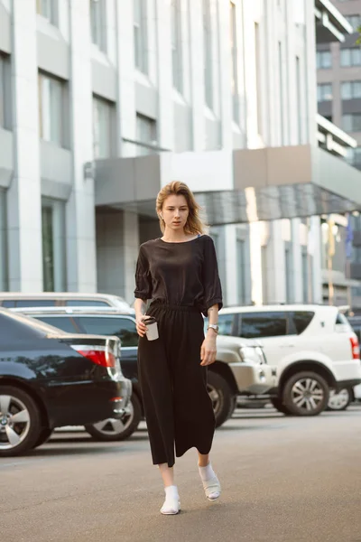 Portrait of serious young woman walking casually on the street n