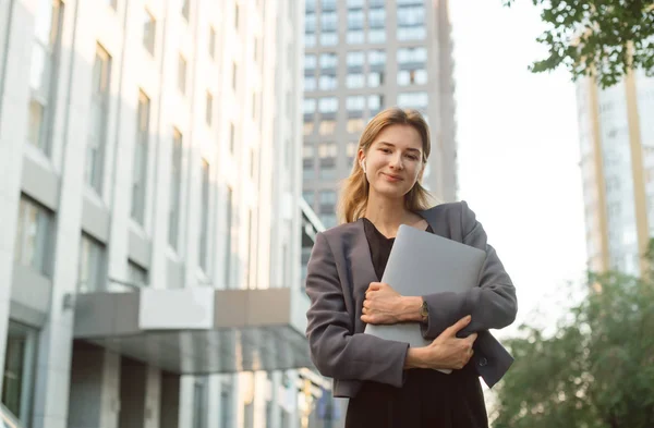 Lächelnde Geschäftsfrau trägt Laptop mit drahtlosen Kopfhörern heraus — Stockfoto