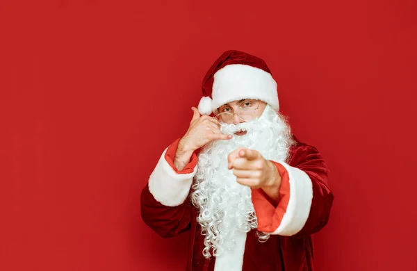 Weihnachtsmann-Gesten rufen mich an. isoliert auf rotem Hintergrund. Neujahrs- und Weihnachtskonzept. Weihnachten. Kopierraum — Stockfoto