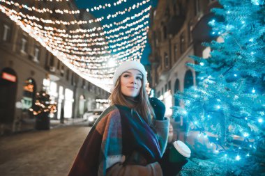 Sıcak elbiseli çekici bir kız yanında bir fincan kahveyle ayakta duruyor.