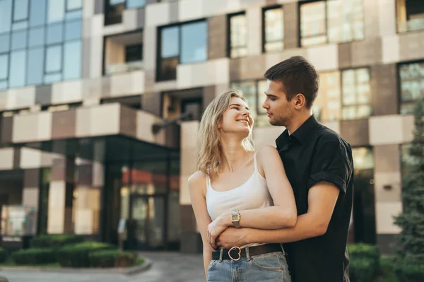 Elegante casal feliz abraçando no fundo urbano, olhando para eac — Fotografia de Stock