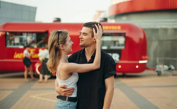 아름다운 커플 이 산책하는 것에 대한 사랑 이야기입니다. 도시의 배경에서 서 서로 바라보고 푸드 트럭의 배경에서 미소짓고 있는 아름다운 행복 한 부부 — 스톡 사진