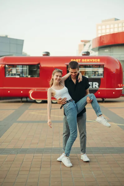 Смешная пара молодой человек и девушка, стоящие на улице против красного F — стоковое фото