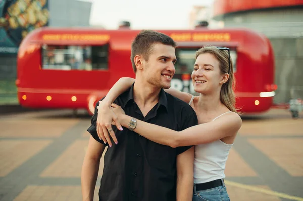 Street portrait of happy couple in stylish casual clothes smilin