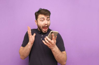 Elinde akıllı bir telefon olan çılgın sakallı bir adamın portresi, ekrana bakıyor ve mor bir arka planda çığlık atıyor. Şok olmuş bir adam akıllı telefon kullanır ve sevinir. İzole edilmiş.