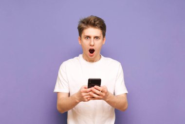 Mavi arka planda duran şok olmuş genç bir adamın portresi.