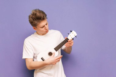 Beyaz tişörtlü konsantre genç adam mavi bir sırt üzerinde duruyor.