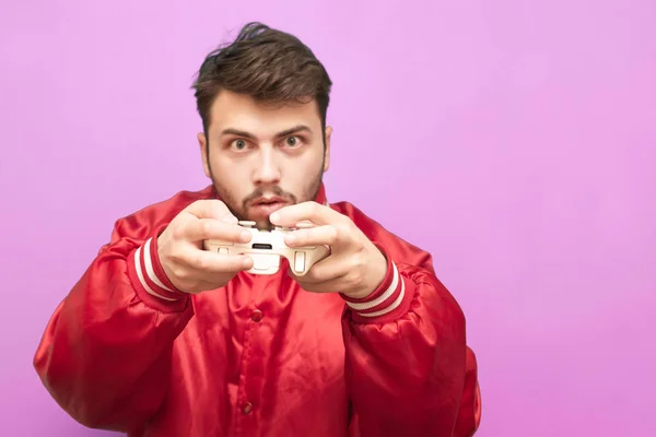 Retrato de um jogador adulto emocional com um joystick na mão sobre um fundo rosa, concentrado na câmera. Concentre-se no gamepad . — Fotografia de Stock