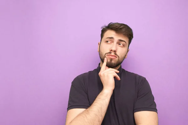 Mann mit Bart und dunklem T-Shirt denkt auf violettem Hintergrund und blickt seitlich in den Raum. nachdenklicher erwachsener Mann ist isoliert auf lila Hintergrund. — Stockfoto