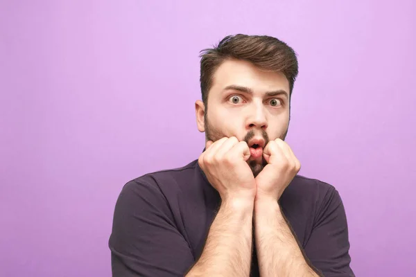 El retrato de cerca de un hombre asustado con barba sobre un fondo púrpura parece sorprendido ante la cámara. Usa una camisa oscura. Aislado . — Foto de Stock