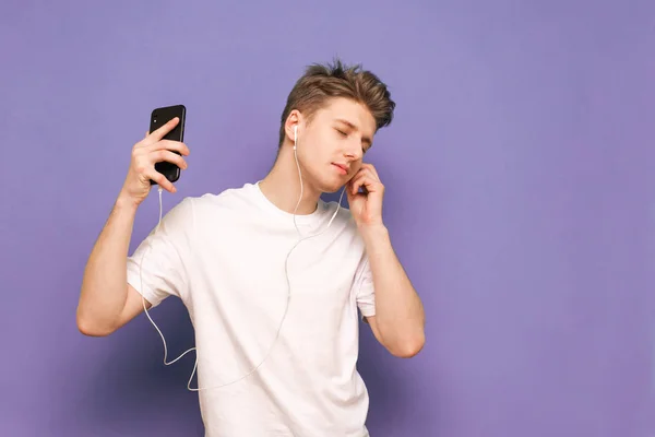 Guapo joven escucha música en sus auriculares con su e —  Fotos de Stock