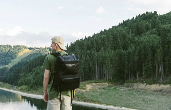 배경에 집중하 세요. 가방을 들고 배낭을 메고 실외로 하이킹을 하는 남자들은 멋진 경치를 감상하면서 산의 울창 한 숲 과 호수를 바라봅니다. 여행, 생활 방식, 모험 개념. — 스톡 사진