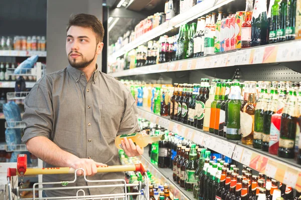 El comprador está en el supermercado en el departamento de alcohol con un bot — Foto de Stock