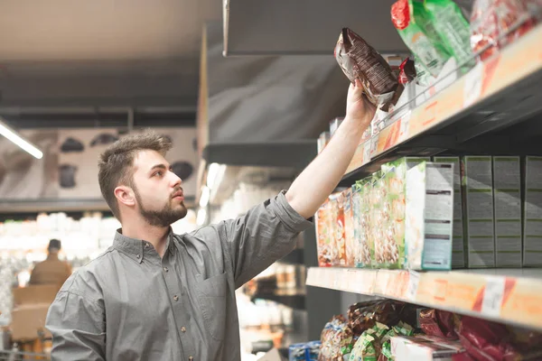 Muž v košili kupuje vločky rychlé snídaně v obchodě s potravinami — Stock fotografie