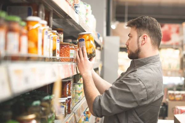 Omul dintr-o barbă este în departamentul de conserve de legume superm — Fotografie, imagine de stoc