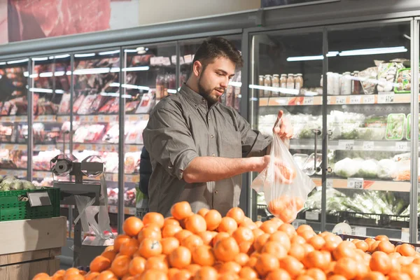 Happy man with a beard stands in a supermarket in the fruit depa — Stock Photo, Image