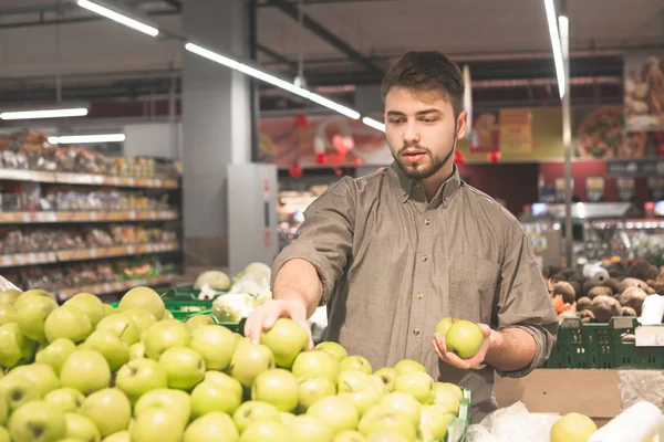 Joven hombre soltero mostrando frutas y verduras en las compras en el supermercado de comestibles - Moderno concepto de estilo de vida saludable con chico en la compra de productos de alimentos biológicos en el mercado vegetariano — Foto de Stock