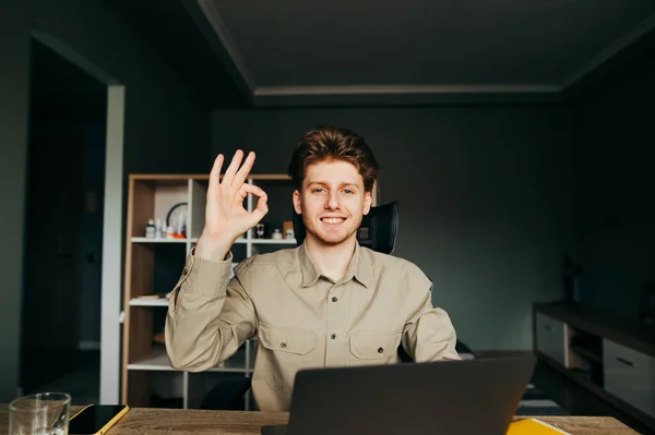 Joven Feliz Sentado Una Mesa Cerca Portátil Casa Muestra Mira — Foto de Stock