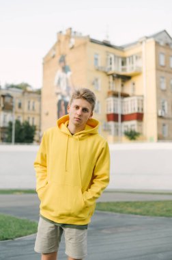 Eski şehrin bisiklet üçgeni mimarisinin arka planında kameraya poz veren şık şık giyinmiş şık genç adam kameraya bakıyor. Dikey.