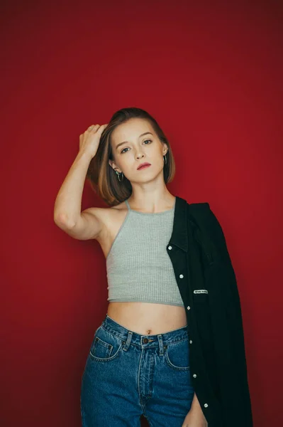 Aantrekkelijk Meisje Jeans Shirt Staat Een Rode Achtergrond Poseert Voor — Stockfoto