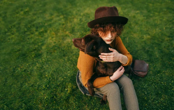 의상을 유행하는 소녀는 동물을 껴안고 공원에서 산책하고 잔디에 컨셉을 좋아함 — 스톡 사진