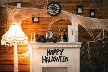 Şömine Cadılar Bayramı için örümcek ağları, mumlar, kafatasları, balkabakları, şamdanlar ve bir kargayla süslenmiş. Cadılar Bayramı için dekorda bir şömine fotoğrafı..