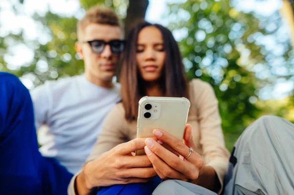 Ζευγάρι Κάθεται Στο Πάρκο Και Χρησιμοποιεί Διαδίκτυο Ένα Smartphone Κοιτάζοντας — Φωτογραφία Αρχείου