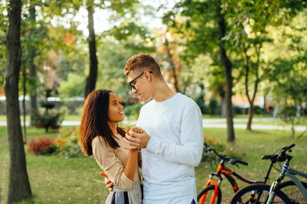 美丽而快乐的一对年轻夫妇在秋天的公园拥抱 彼此凝视着 面带微笑 一对笑容可亲的年轻夫妇在公园里度过时光的画像 — 图库照片