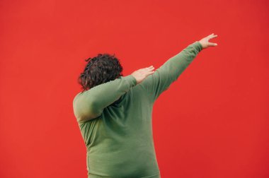 Kırmızı duvar arka planında dans eden gündelik kıyafetli komik şişman adam. İzole edilmiş. Kapat.