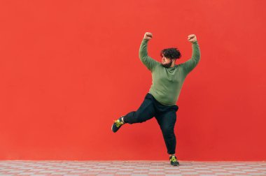 Komik şişman dansçı kulaklıkla müzik dinler ve kırmızı arka planda dans eder, fotokopi alanına bakar. Şişman adam kırmızı duvarın arkasında dans gösterisi sergiliyor..