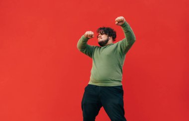 Sıradan kıyafetlerle dans eden ve kulaklıkla müzik dinleyen şişman, izole genç bir adam. Şişman adam kırmızı duvarın arkasında dans gösterisi yapıyor..