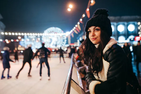 Χαριτωμένο Κορίτσι Ένα Καπέλο Και Χειμωνιάτικα Ρούχα Στέκεται Κοντά Παγοδρόμιο — Φωτογραφία Αρχείου