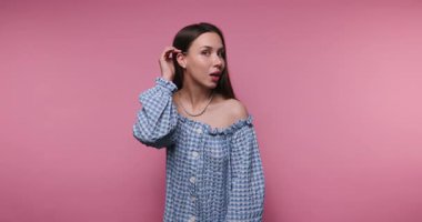 Bir kadın zarif, mavi bir elbisenin içinde omuzları açık bir şekilde duruyor ve kendine has tarzını canlı pembe bir arka plana yansıtıyor. Duruşu özgüveni ve duruşunu yansıtıyor..