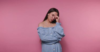 Uzun siyah saçlı genç bir kadın mavi ve beyaz kareli bir elbise giyerken bir anlık yansıma gösterir. Yumuşak pembe arka plan onun düşünceli tavrını arttırıyor ve bunu çarpıcı bir görüntü haline getiriyor..