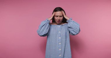 Genç bir kadın, neşeli ve renkli bir ortamda başını tutarken hayal kırıklığını ve üzüntüsünü ifade eder. İlgili duyguları yumuşak bir şekilde sergiliyor..