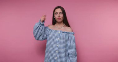 Genç bir kadın canlı pembe bir arka plana karşı duruyor. Karışık bir kafa karışıklığı ve hoşnutsuzluk gösteriyor. Omzunun üstü o anda çekilen neşeli ama şaşkın ifadeye ekleniyor..